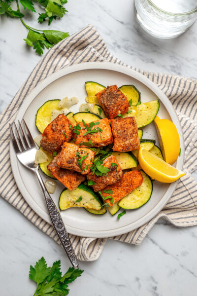 An air fryer salmon recipe served on a white plate with a cloth napkin.