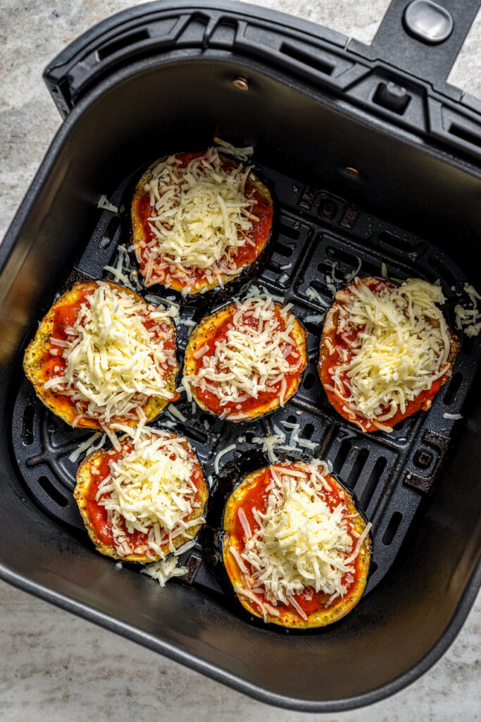 This saucy air fryer eggplant parmesan recipe with fresh mozzarella is the perfect veggie appetizer for dinner parties. Adding the sauce and cheese to the eggplants.
