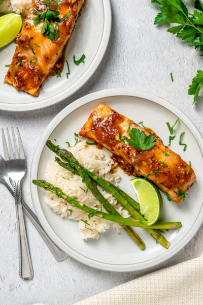 Salmon portions with asparagus and rice on white dinner plates.