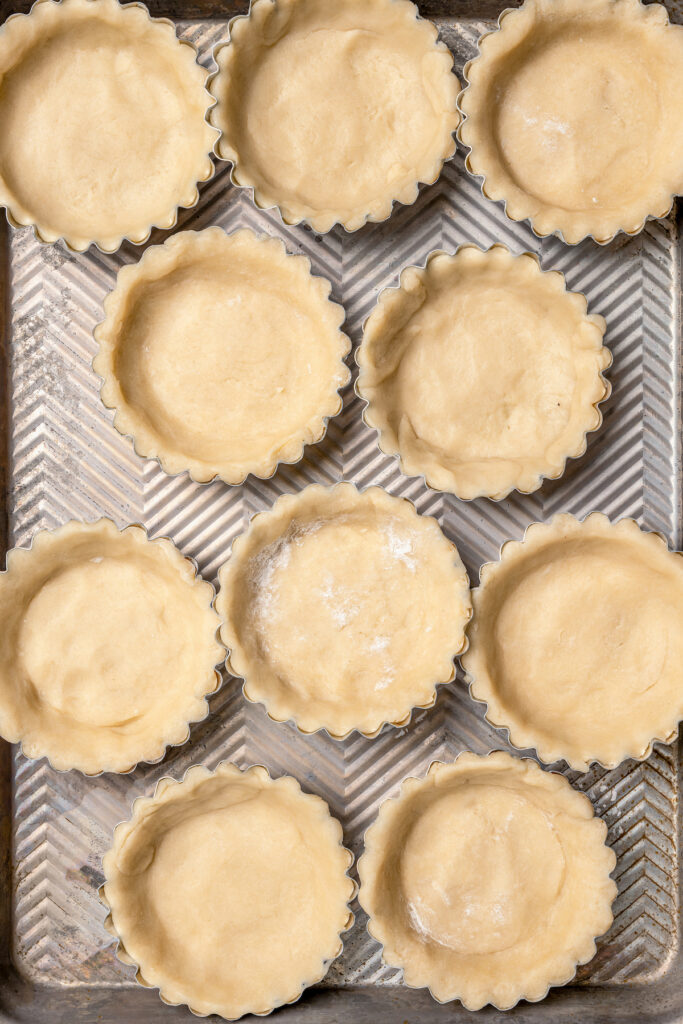 This asparagus tartlets recipe with zesty parmesan custard and buttery crust is an easy way to impress guests for brunch. Dough pressed into the tart pans.