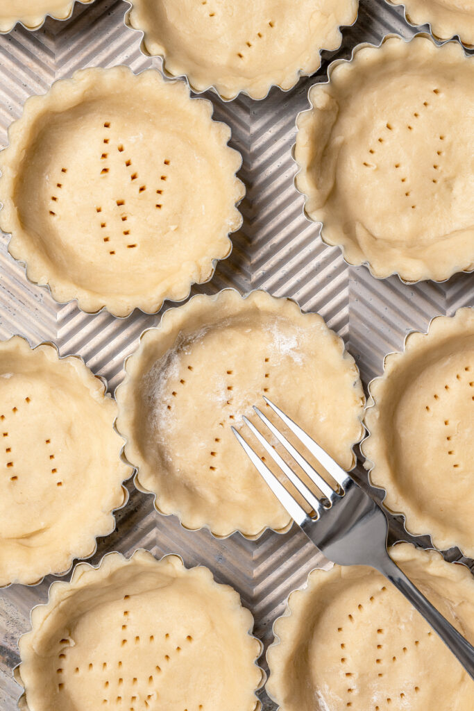 This asparagus tartlets recipe with zesty parmesan custard and buttery crust is an easy way to impress guests for brunch. Poking the dough with a fork.