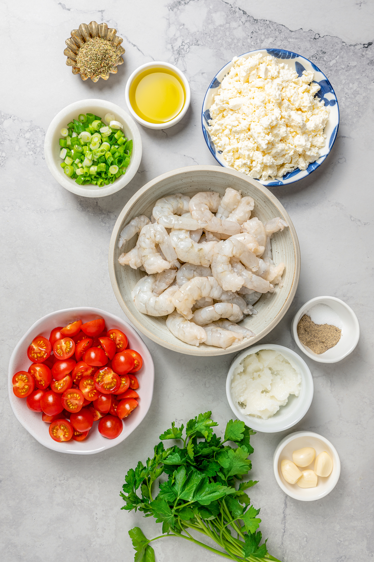 Baked Shrimp with Tomato and Feta is an easy, gluten free, healthy dinner that is made in one skillet and ready in less than 30 minutes. Baked shrimp ingredients measured and arranged on a work surface.