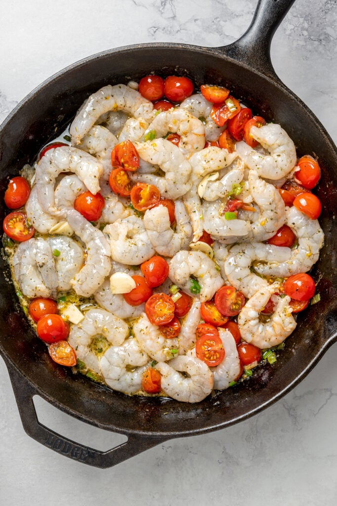 Baked Shrimp with Tomato and Feta is an easy, gluten free, healthy dinner that is made in one skillet and ready in less than 30 minutes. Adding shrimp to the skillet of tomatoes and aromatics.