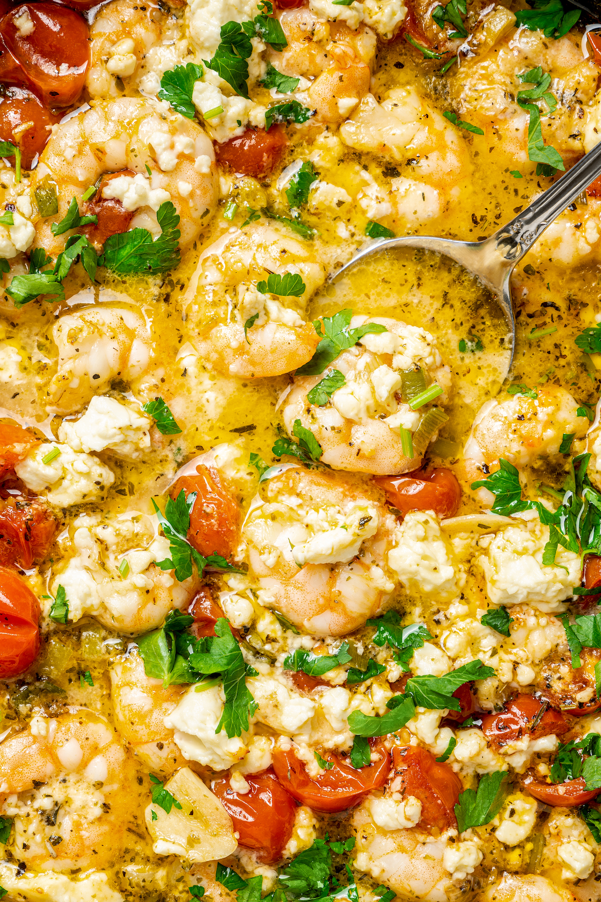 Baked Shrimp with Tomato and Feta is an easy, gluten free, healthy dinner that is made in one skillet and ready in less than 30 minutes. Close-up shot of homemade shrimp with garlic, herbs, tomatoes, and feta.