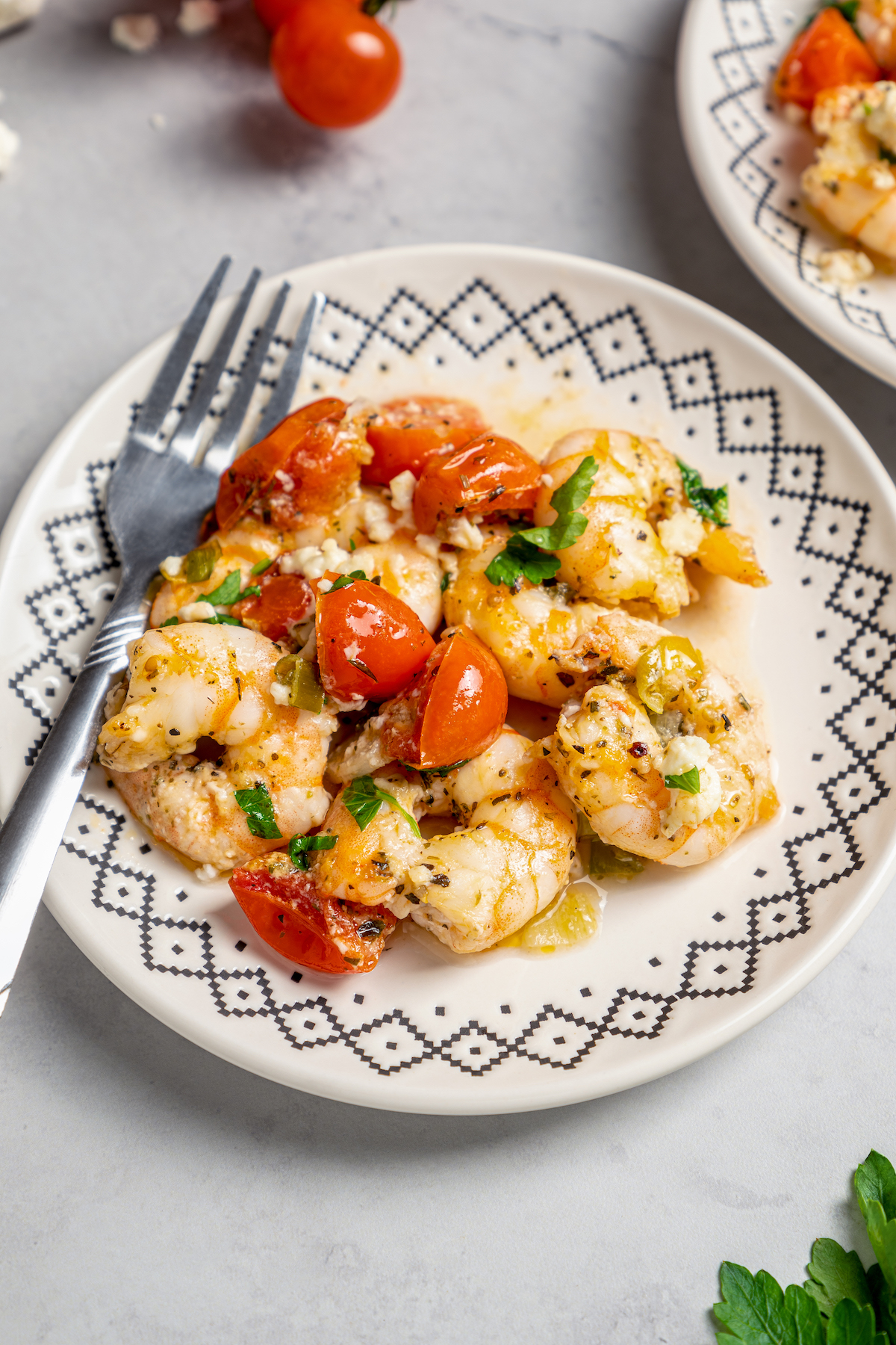 Baked Shrimp with Tomato and Feta is an easy, gluten free, healthy dinner that is made in one skillet and ready in less than 30 minutes. Baked shrimp served on a blue and white dinner plate.