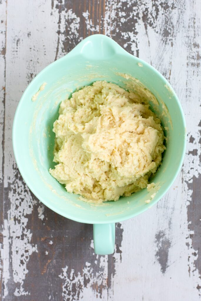 These are the perfect Gluten Free Lemon Poppyseed Muffins. Real lemon and crunchy poppy seeds in a tender, sweet muffin. Easy to make! A thick muffin batter in a mint-colored mixing bowl.