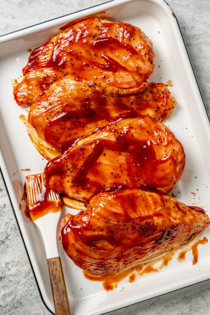 This juicy, grilled BBQ chicken recipe is coated in your favorite barbecue sauce for a sweet-and-savory cookout dinner. Brushing the cooked chicken with BBQ sauce.