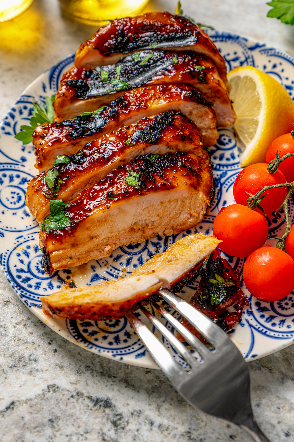 This juicy, grilled BBQ chicken recipe is coated in your favorite barbecue sauce for a sweet-and-savory cookout dinner. Juicy, sliced BBQ chicken recipe on a serving plate.