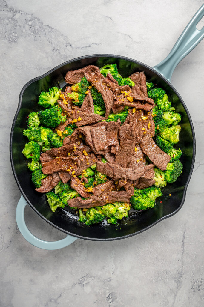 This beef and broccoli recipe with honey, garlic, and red pepper flakes is a spicy, saucy Asian-style dinner that beats take-out any day. Mixing the broccoli and beef in the pan.