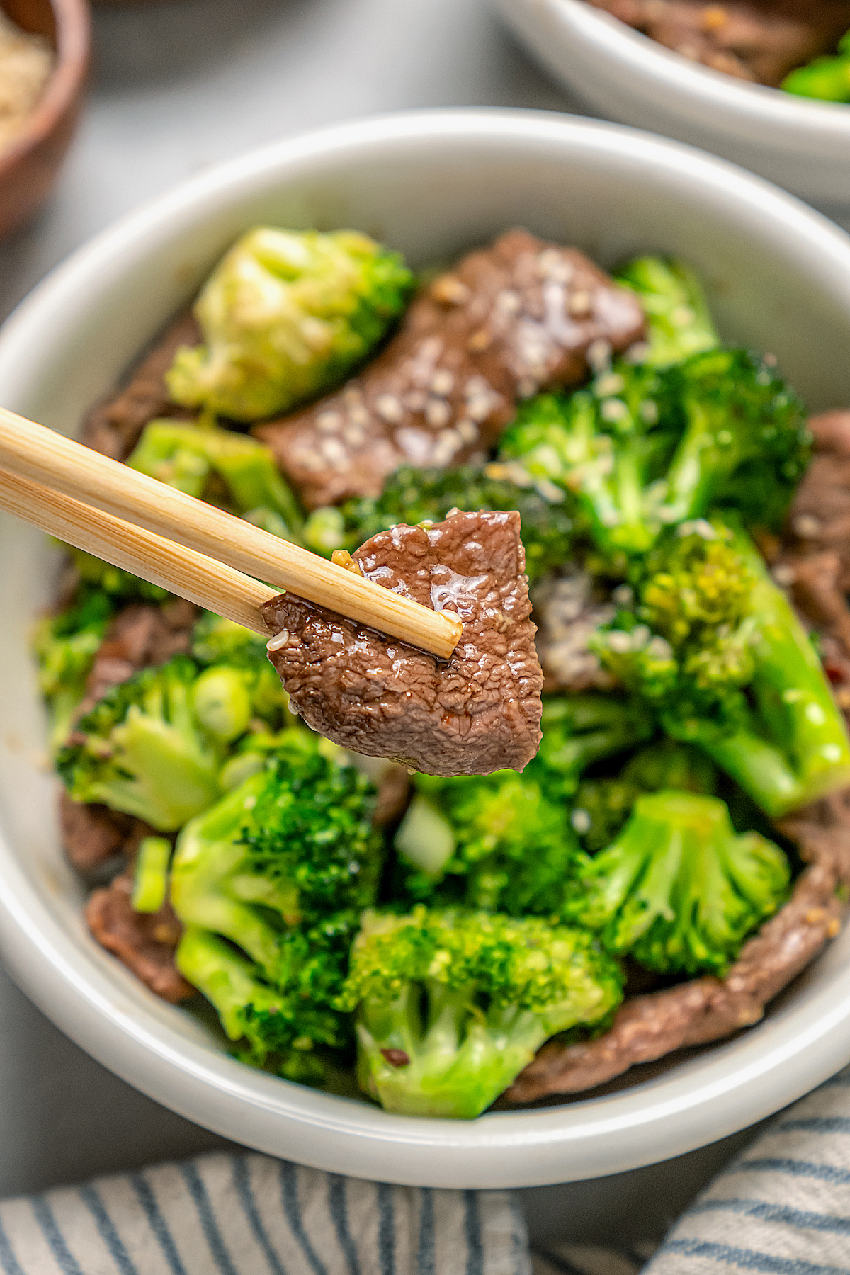 This beef and broccoli recipe with honey, garlic, and red pepper flakes is a spicy, saucy Asian-style dinner that beats take-out any day. Grabbing a piece of beef with chopsticks.