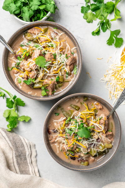 Bowls of Brazilian beef stew on a table with fresh herbs and cheese.