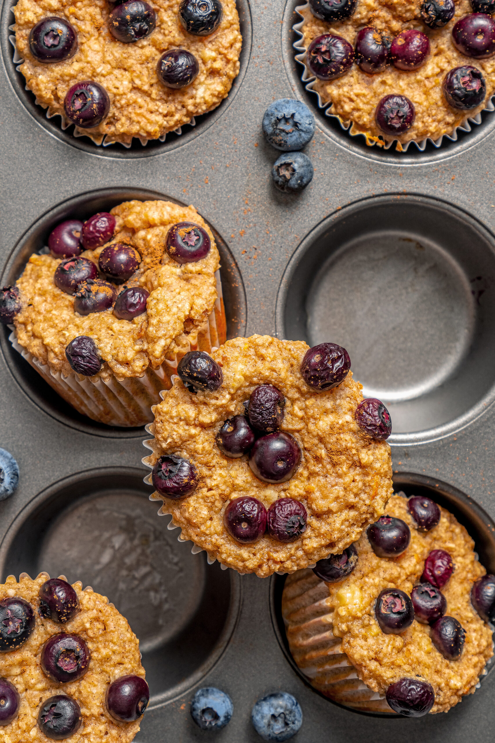This naturally-sweetened blueberry protein muffins recipe with cinnamon and orange zest is a great on-the-go breakfast. Freshly baked blueberry protein muffins in the muffin tray.