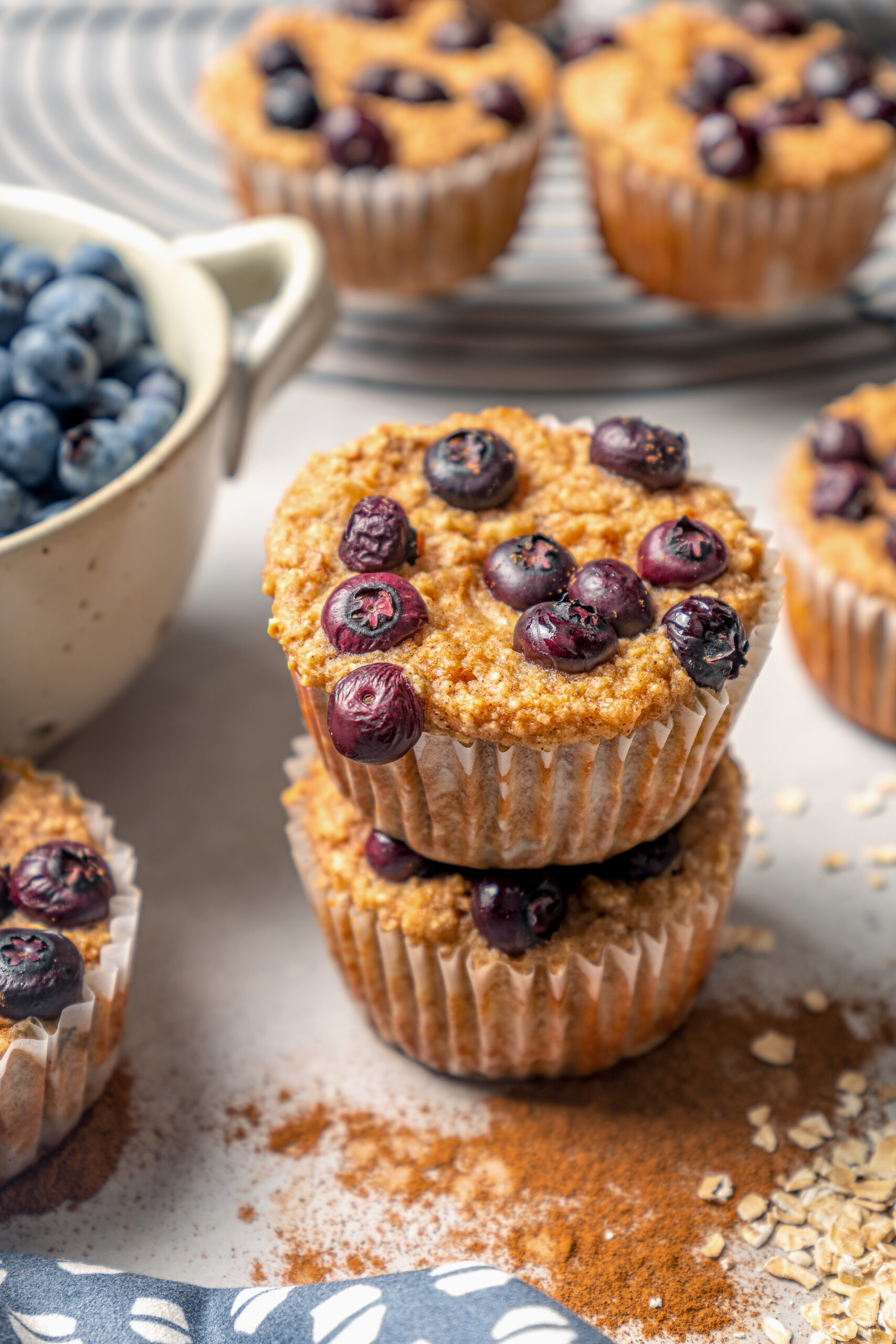 This naturally-sweetened blueberry protein muffins recipe with cinnamon and orange zest is a great on-the-go breakfast. Two stacked blueberry protein muffins.