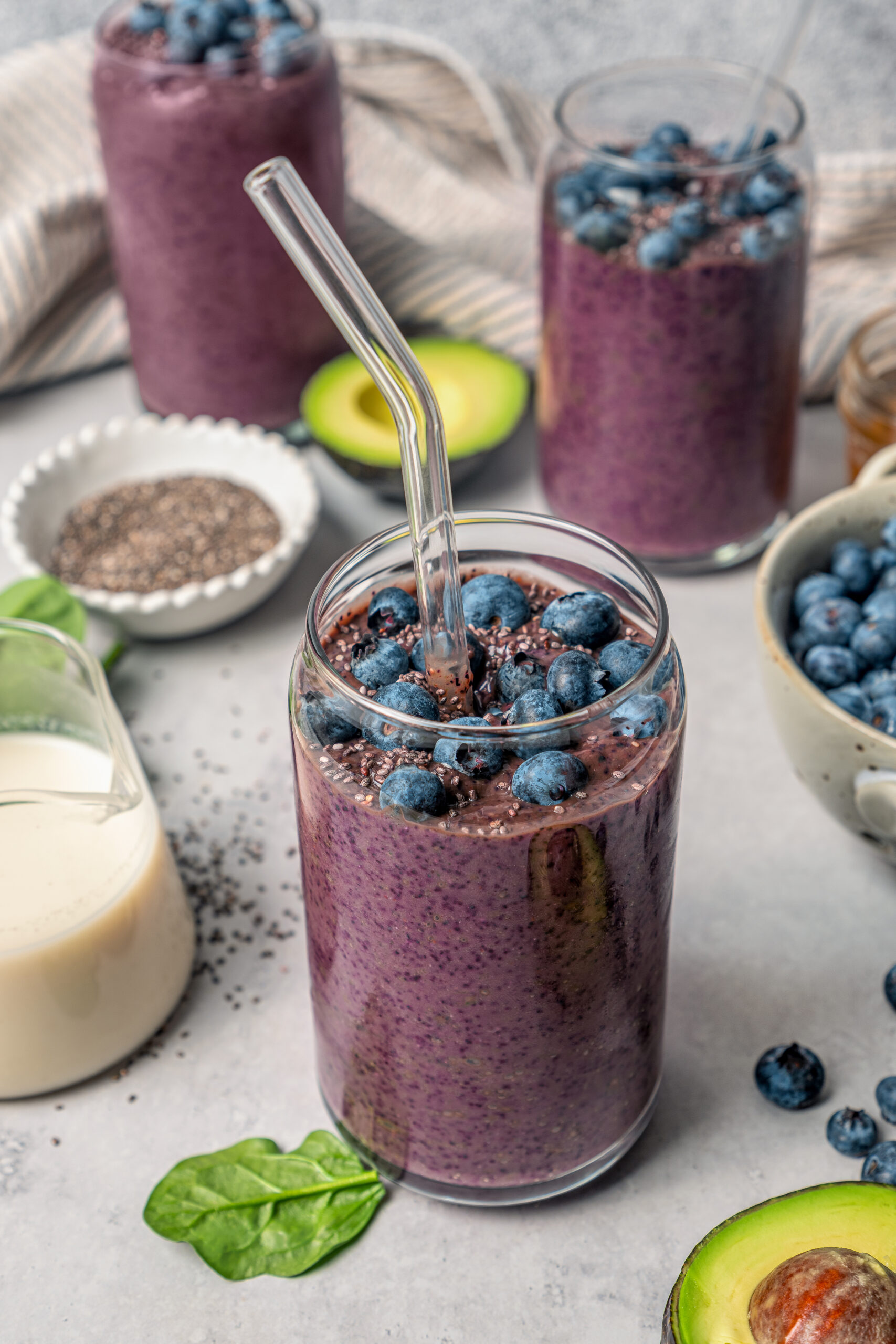This blueberry-chia superfood smoothie recipe with spinach, avocado, and honey is the perfect way to start your mornings. Blueberry superfood smoothie topped with fresh blueberries in a serving glass.