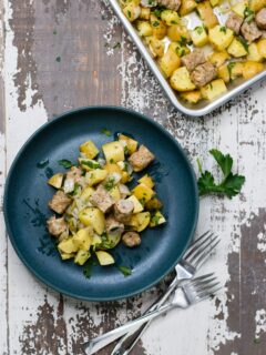Breakfast potatoes and sausage on a small plate, next to a sheet pan.