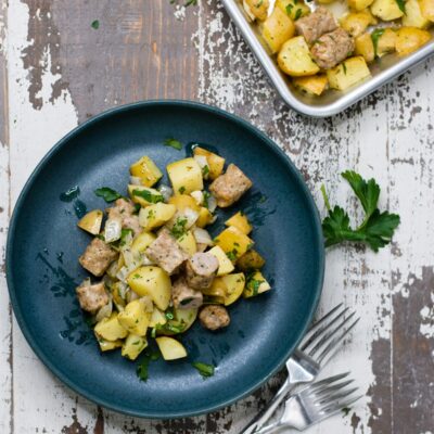 Breakfast potatoes and sausage on a small plate, next to a sheet pan.