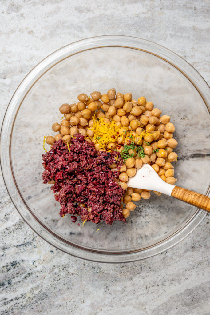 This zesty chickpea bruschetta recipe with herby pesto and salty olives on toasty bread is a 20-minute summer appetizer. Adding the chickpea mixture ingredients to a bowl.