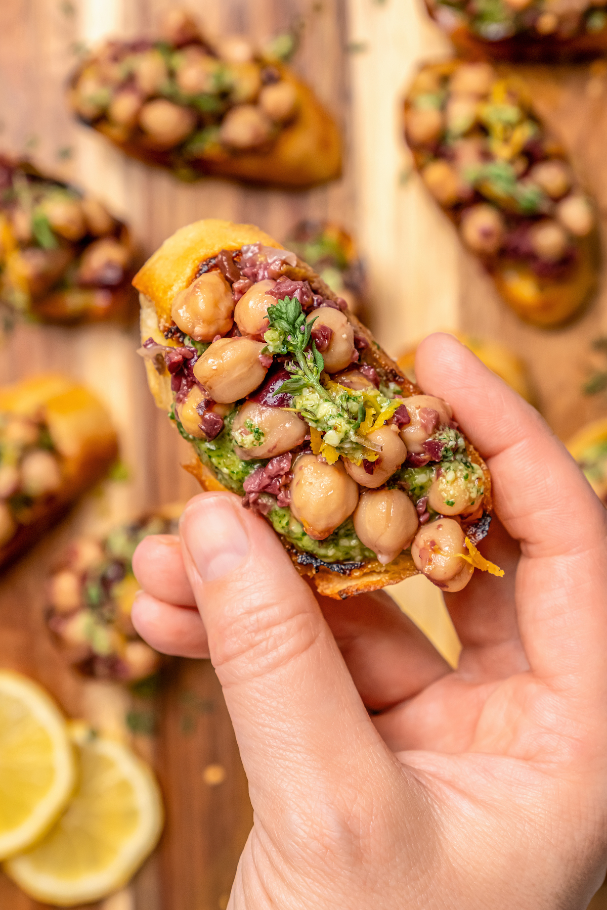 This zesty chickpea bruschetta recipe with herby pesto and salty olives on toasty bread is a 20-minute summer appetizer. Grabbing a bruschetta with tangy olive-chickpea mixture on top.