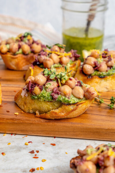 Close-up of chickpea bruschetta with lemon zest and fresh thyme on top.
