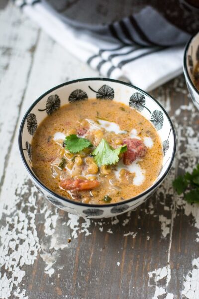 A blue-and-white bowl filled with lentil soup, and topped with coconut milk and cilantro leaves.