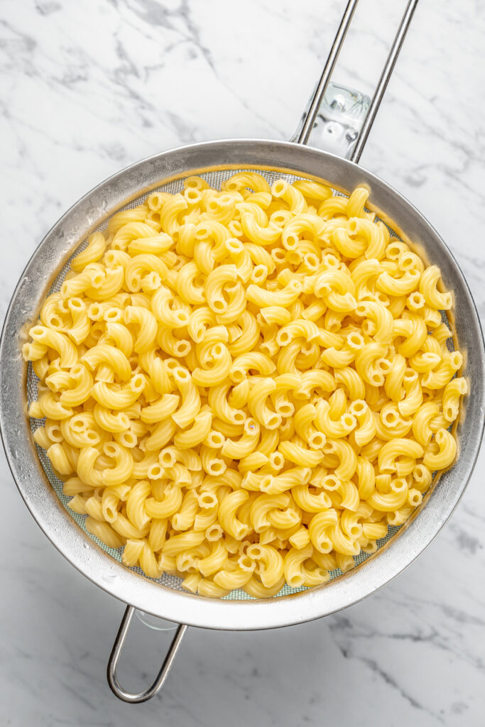 This Creamy Mac and Cheese with Jalapeño and Corn is a little spicy, a little sweet, and very, very cheesy. Irresistible and easy to make! Cooked elbow macaroni in a colander.