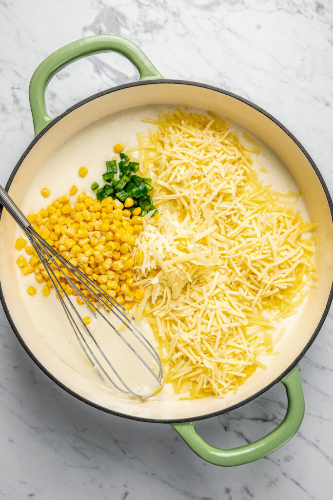 This Creamy Mac and Cheese with Jalapeño and Corn is a little spicy, a little sweet, and very, very cheesy. Irresistible and easy to make! Adding corn, jalapeno, cheese, and seasonings to cheese sauce.