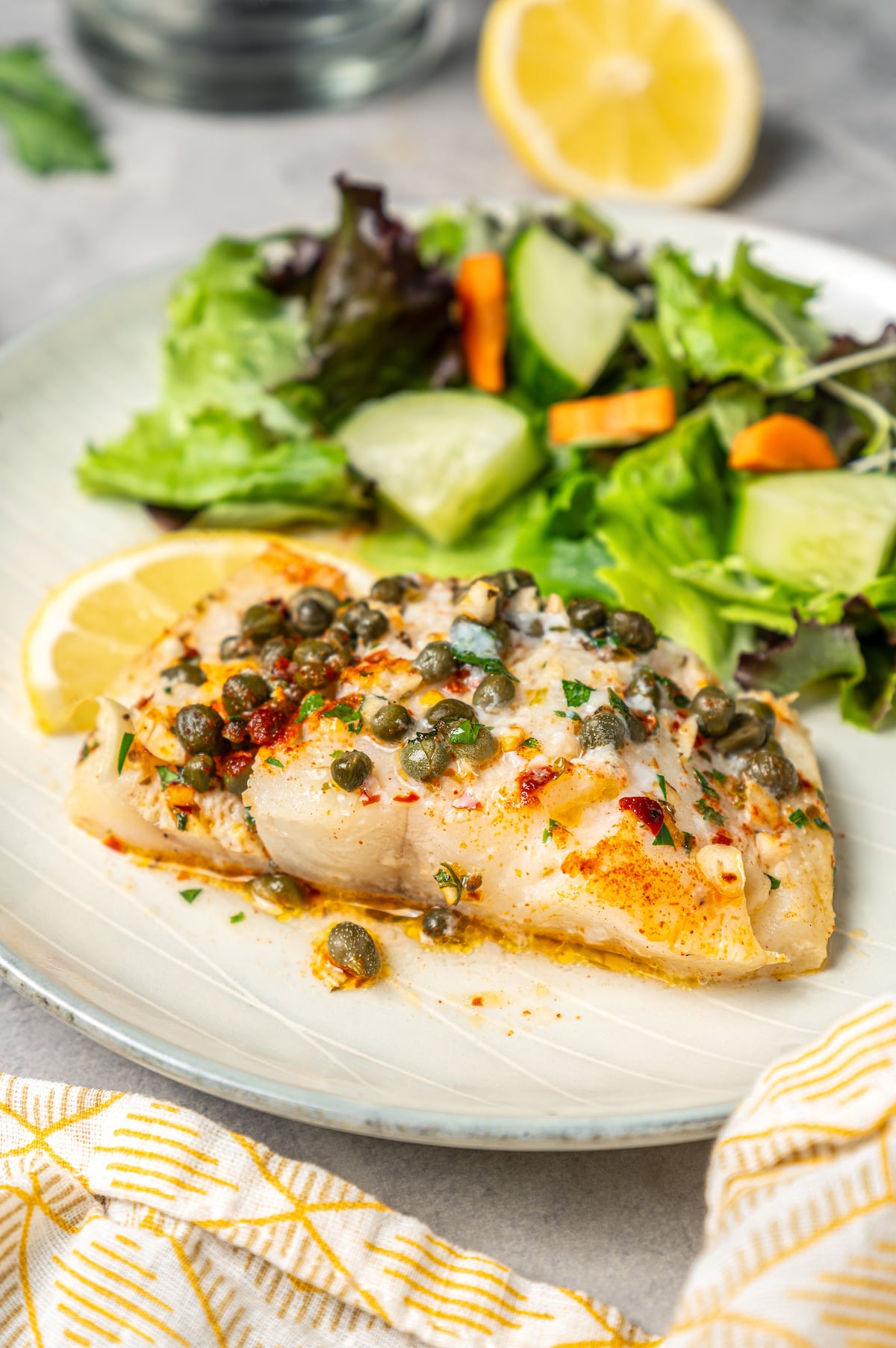 You'll crave the light, fresh flavors of this easy Baked Cod Recipe. Simple prep, perfect texture, and zingy flavor - what could be better? Easy baked cod recipe, served with green salad.