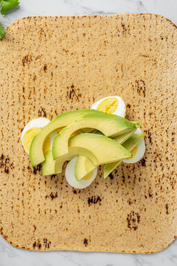 This Egg and Avocado Breakfast Wrap is low-carb and loaded with protein. Healthy, clean, and delicious, it’s a quick breakfast you'll crave! Slices of avocado and egg on a breakfast wrap.