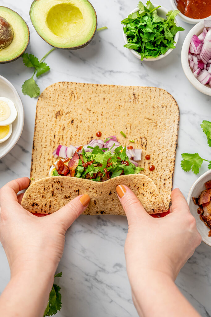 This Egg and Avocado Breakfast Wrap is low-carb and loaded with protein. Healthy, clean, and delicious, it’s a quick breakfast you'll crave! Rolling up a Flatout wrap with breakfast fillings.