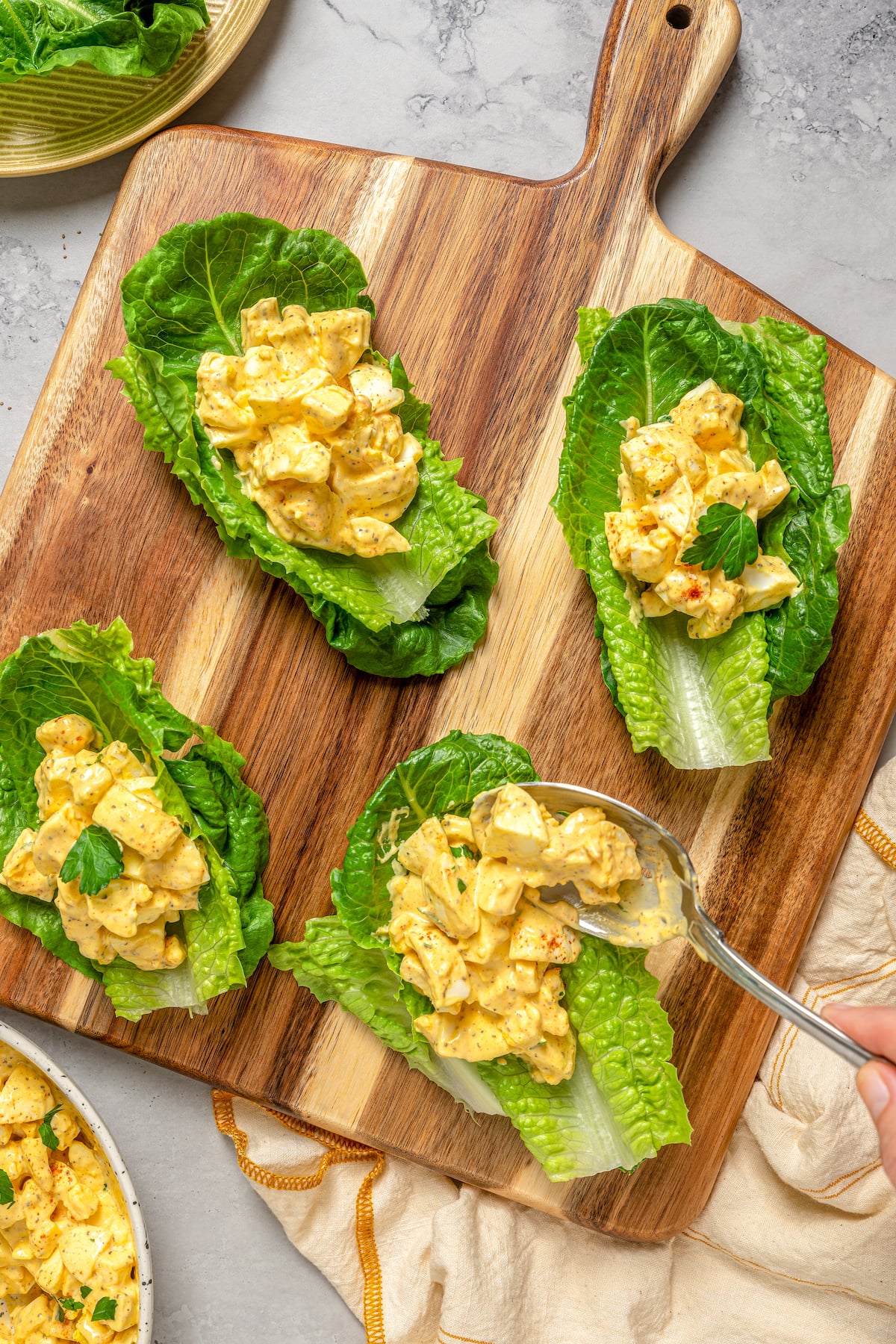 This Healthy Egg Salad is a simple, tasty recipe that’s packed with protein and easy to prepare. A scrumptious lunch or midday snack! Adding the salad to individual lettuce leaves.
