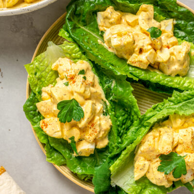 Portions of healthy egg salad spooned onto romaine leaves.