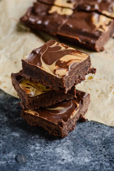 A stack of three flourless peanut butter protein brownies on a granite countertop