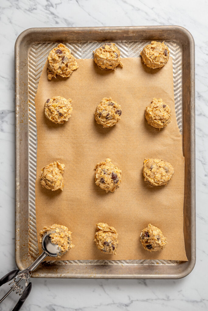 This banana oatmeal chocolate chip cookies recipe is warmly spiced with cinnamon and cardamom for a comforting, freshly baked treat. Scooping balls of dough onto the prepared baking sheet.