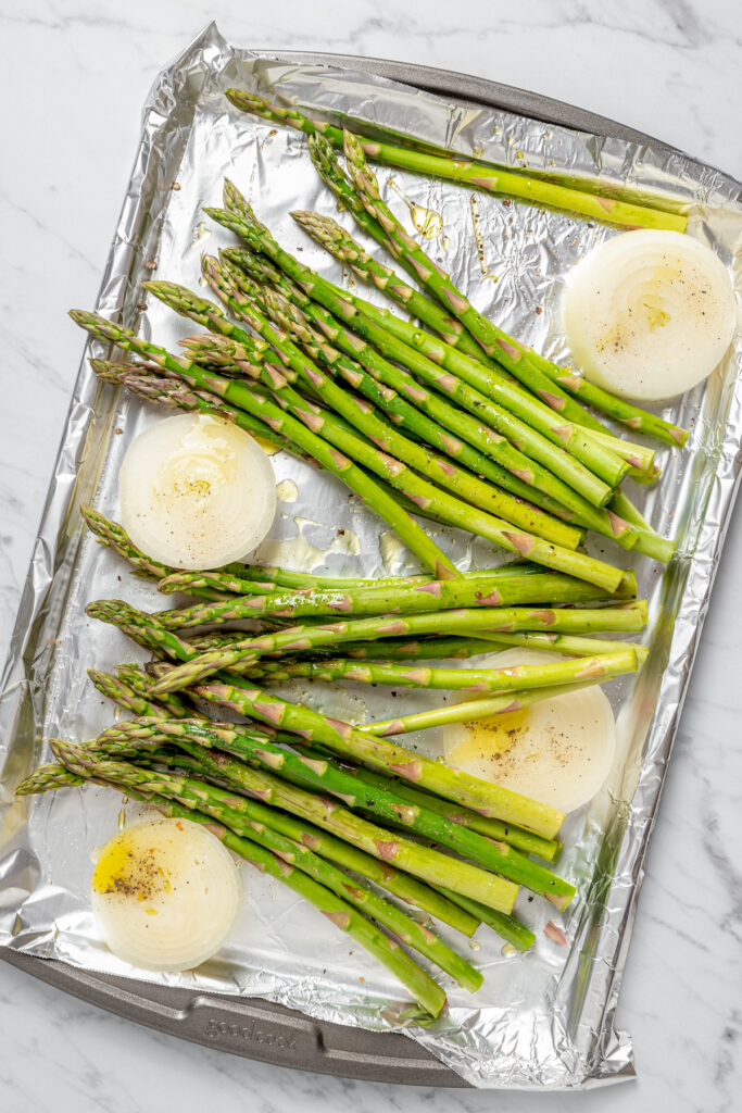 Grilled Asparagus with Onion recipe is topped with simple vinaigrette, blue cheese, black Mission figs, and toasted pine nuts. So flavorful! Seasoned asparagus and onion, ready for grilling.
