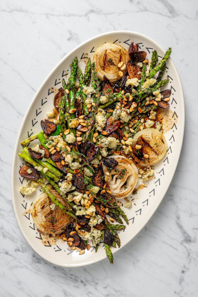 A platter of grilled vegetables topped with blue cheese, figs, and pine nuts.