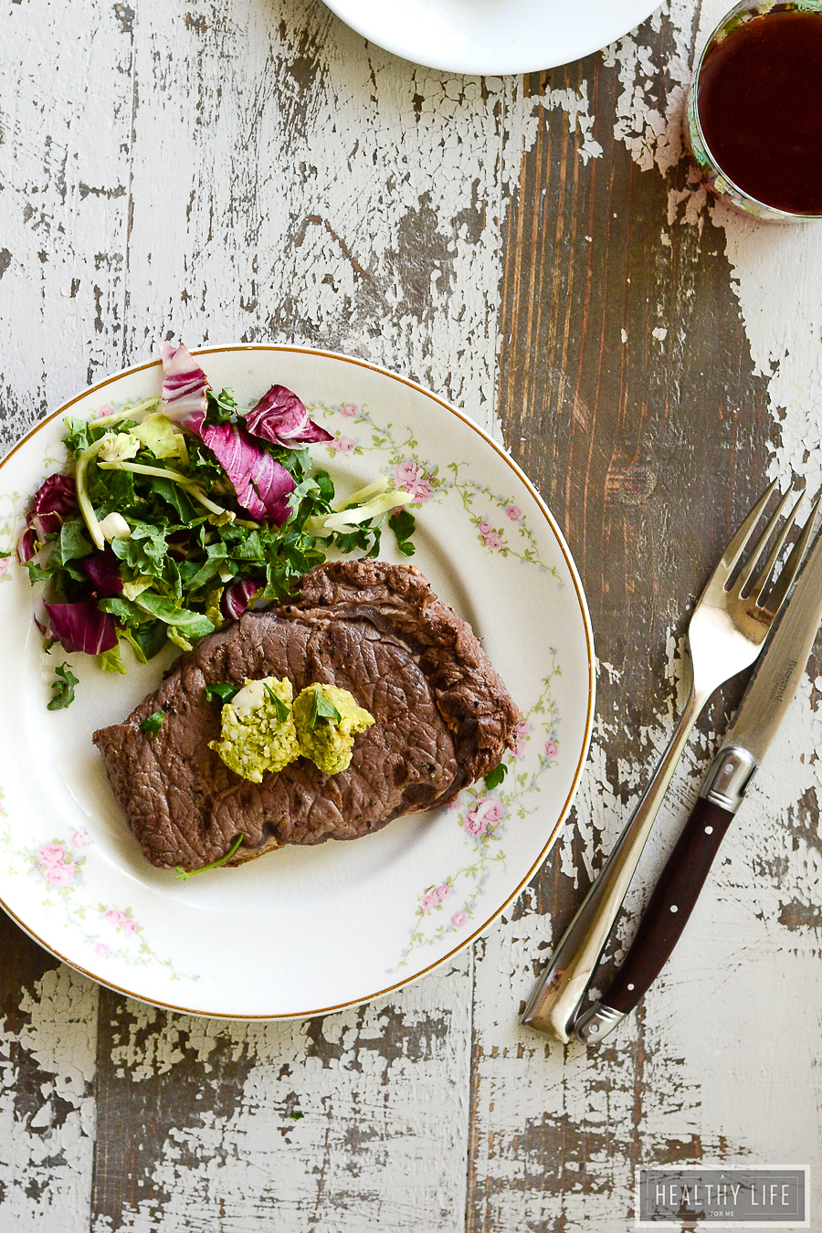 This juicy, 10-minute bison steak recipe with avocado butter will keep you busy at all your cookouts this year. Whole bison steak with avocado butter on top and a salad on the side.
