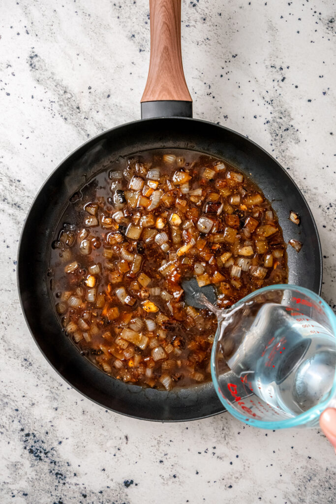 This perfectly juicy grilled chicken recipe with homemade sweet-and-savory sauce is an easy Asian-style dinner. Pouring water into the sauteed onion mixture in the skillet.