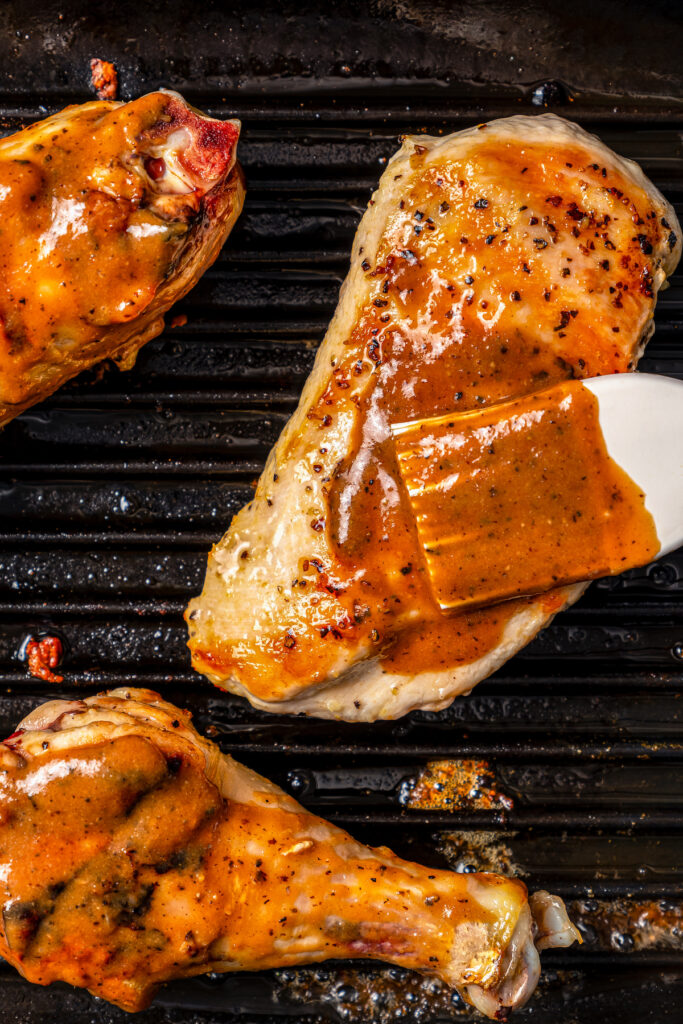 This perfectly juicy grilled chicken recipe with homemade sweet-and-savory sauce is an easy Asian-style dinner. Brushing BBQ sauce on the chicken as it grills.