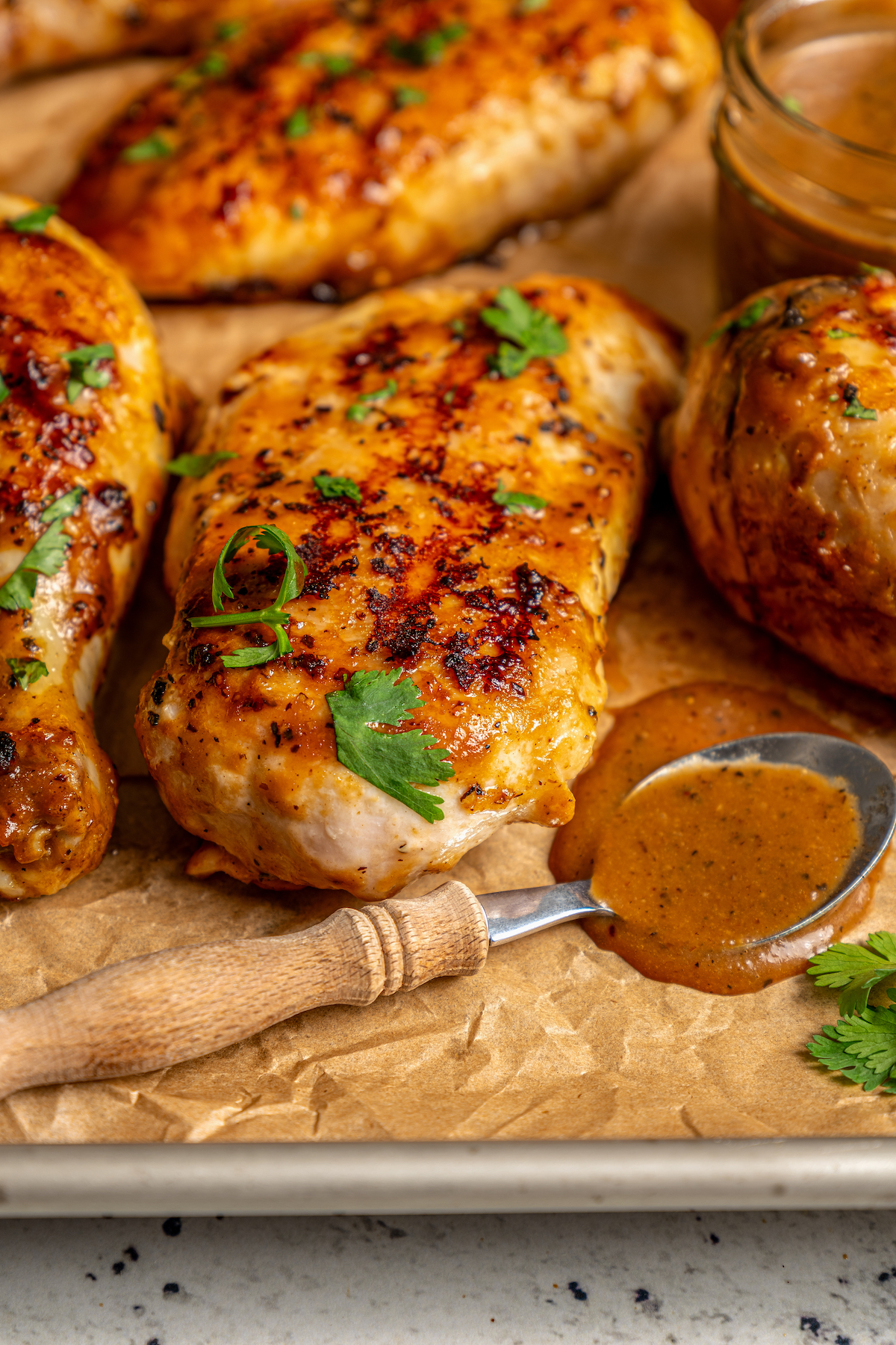 This perfectly juicy grilled chicken recipe with homemade sweet-and-savory sauce is an easy Asian-style dinner. Grilled chicken on a baking tray with Asian BBQ sauce.