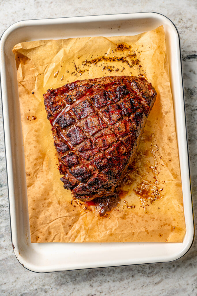 This juicy grilled tri tip recipe with homemade Sicilian herb sauce is an easy dinner for your next summer cookout. Whole grilled roast on a baking sheet.