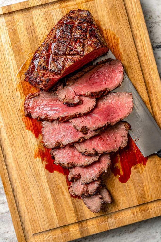 This juicy grilled tri tip recipe with homemade Sicilian herb sauce is an easy dinner for your next summer cookout. Thinly slicing the beef roast after grilling.