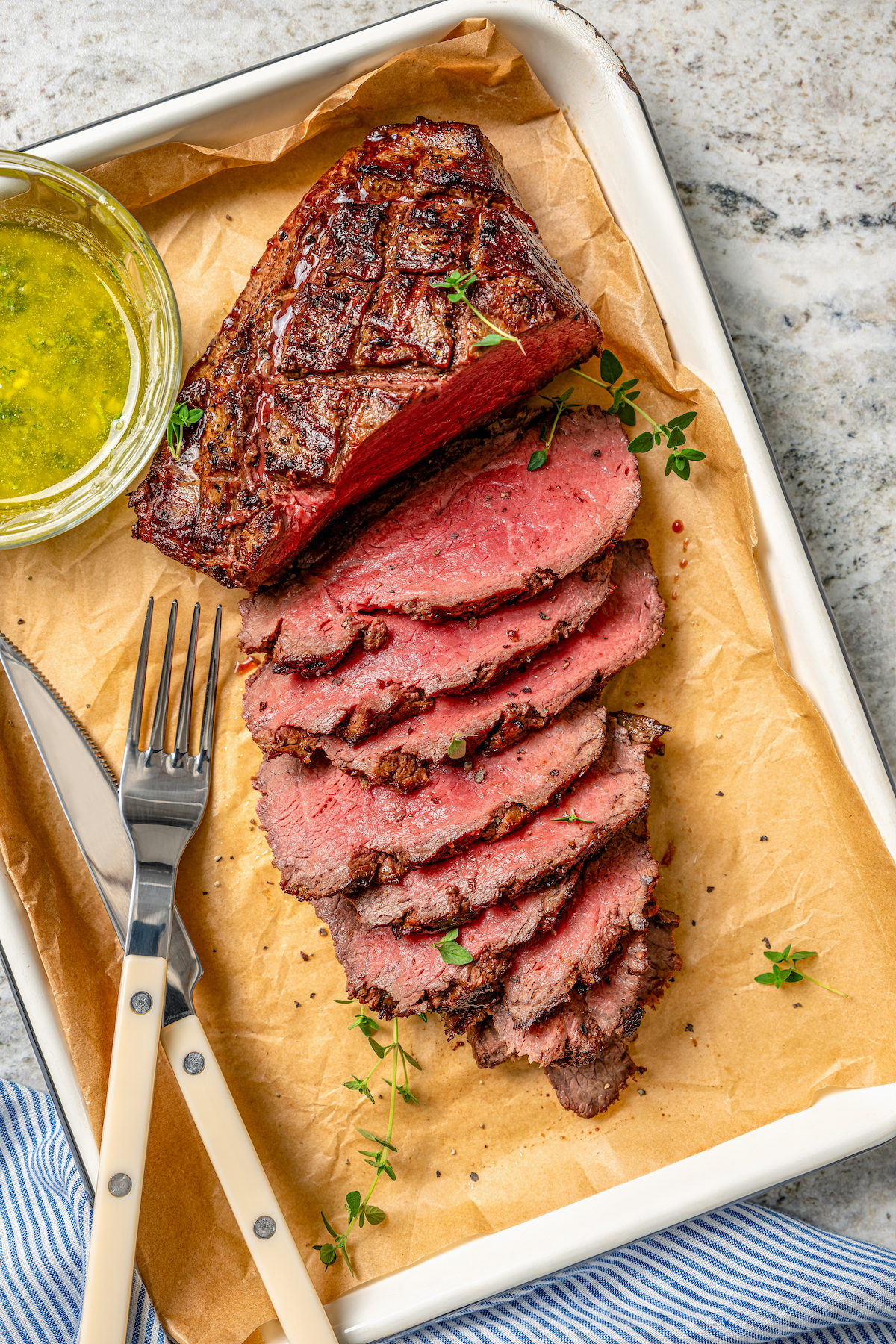 This juicy grilled tri tip recipe with homemade Sicilian herb sauce is an easy dinner for your next summer cookout. Sliced tri tip with a small bowl of herb sauce on the side.