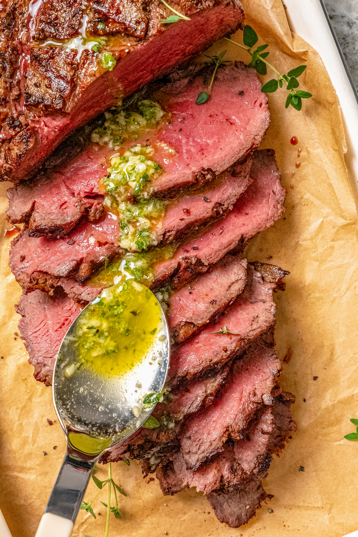 This juicy grilled tri tip recipe with homemade Sicilian herb sauce is an easy dinner for your next summer cookout. Spooning Sicilian herb sauce over the sliced, grilled tri tip.