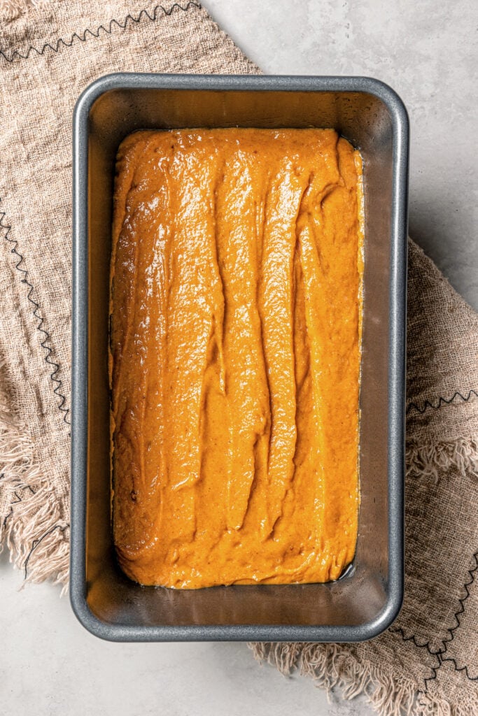 This spiced pumpkin bread recipe with whole-wheat flour, creamy yogurt, and brown sugar is the perfect fall-flavored breakfast. Pumpkin bread batter in the prepared loaf pan.