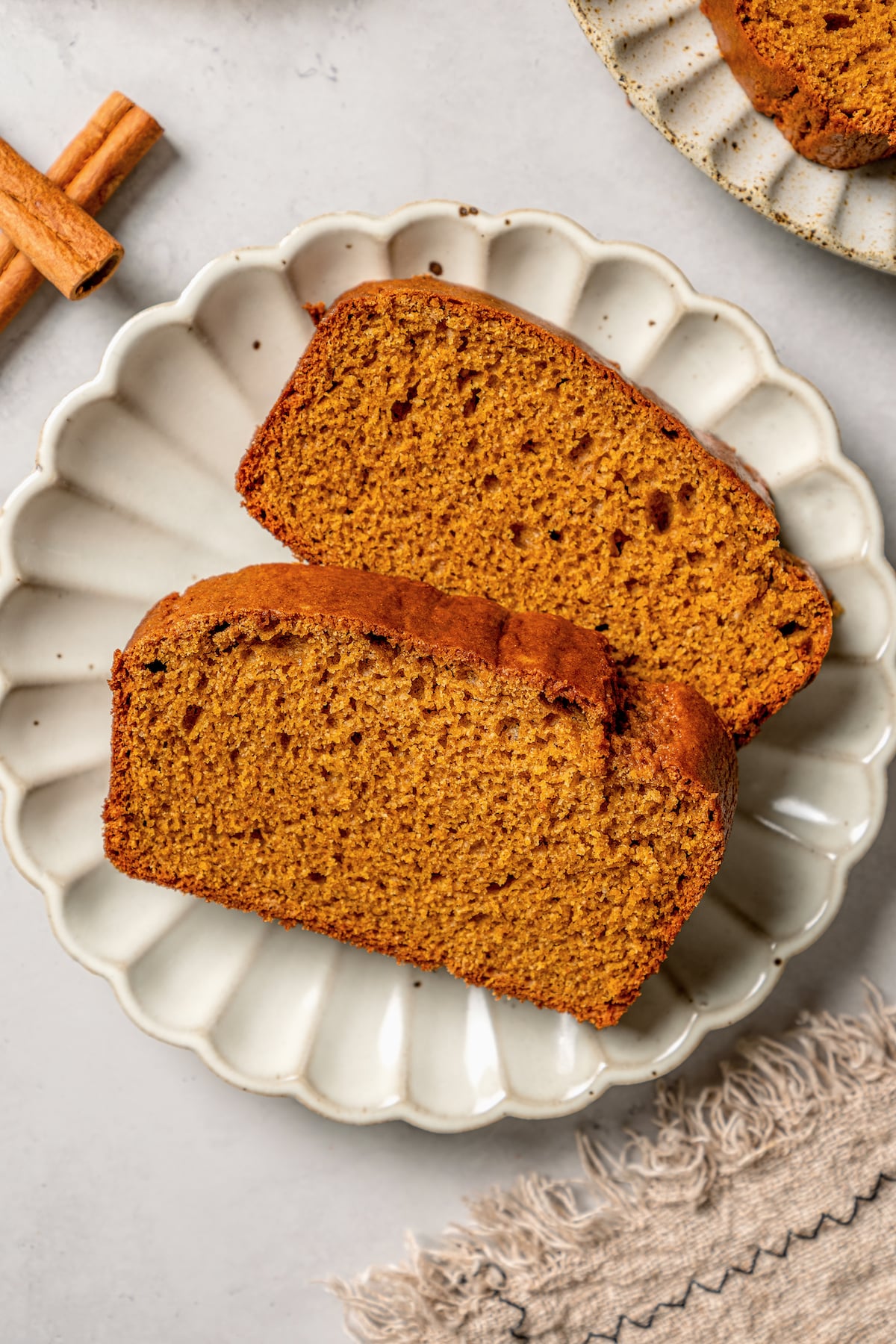 This spiced pumpkin bread recipe with whole-wheat flour, creamy yogurt, and brown sugar is the perfect fall-flavored breakfast. Two slices of pumpkin breakfast loaf with warm spices and brown sugar.