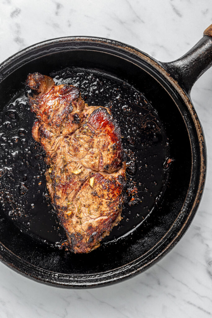 This Pan Seared Steak Recipe with Roasted Vegetables is hearty, filling, and easy to make. A crazy-good marinade brings it all together! Searing a steak in a skillet.