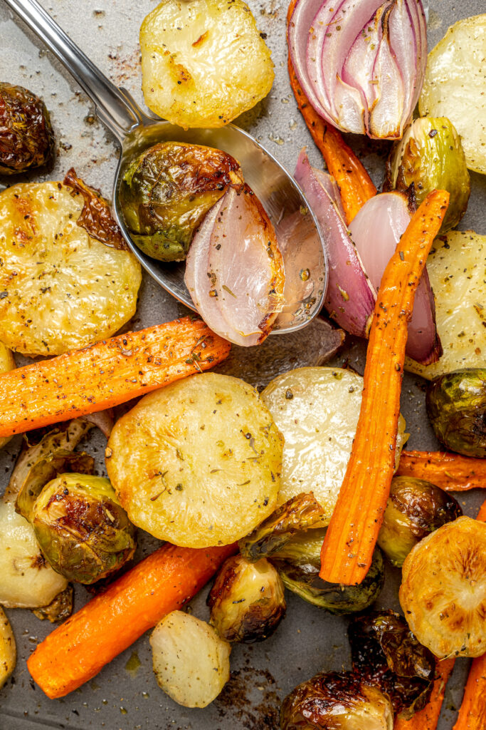 This Pan Seared Steak Recipe with Roasted Vegetables is hearty, filling, and easy to make. A crazy-good marinade brings it all together! Roasted potatoes, carrots, and brussels sprouts on a baking sheet.