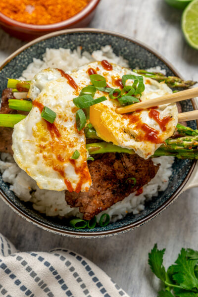 Lifting a piece of egg out of a bowl with chopsticks.