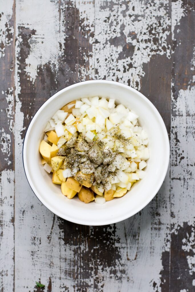 Seasoned potatoes, tender onions, and hearty sausage make this recipe for Baked Breakfast Potatoes with Sausage is a true crowd-pleaser. Mixing onions, potatoes, seasonings, and other ingredients in a large bowl.