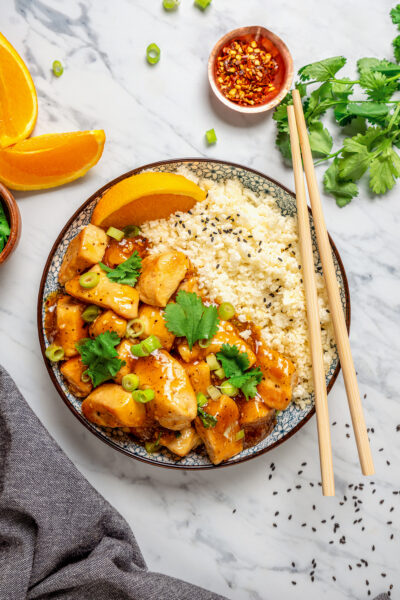 Bowl of orange chicken with cauliflower rice.